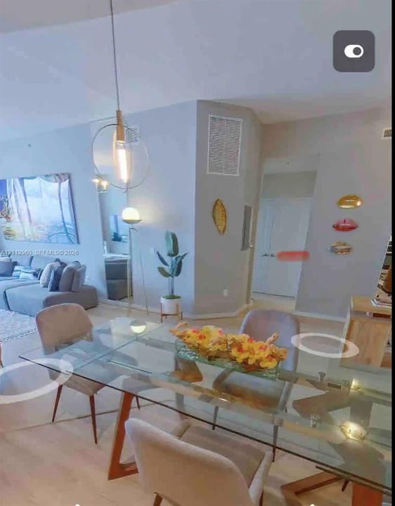 Open-concept interior featuring light wood-finish flooring, high ceilings, and a suspended metal-frame pendant light fixture