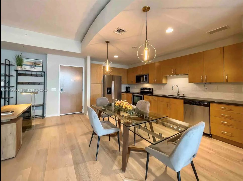 Kitchen featuring flat-panel wood cabinetry, dark stone countertops, stainless steel appliances, recessed lighting, and geometric pendant light fixtures