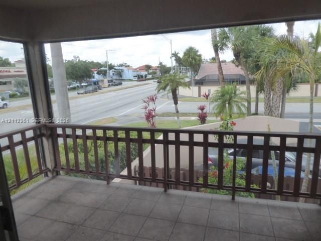 Covered balcony featuring concrete tile flooring and a brown metal railing