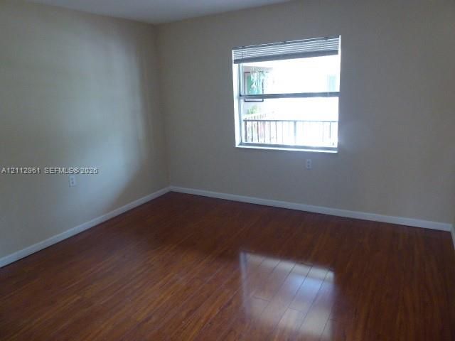 Room featuring wood-finish flooring, neutral wall paint, and a single-pane window with attached horizontal blinds