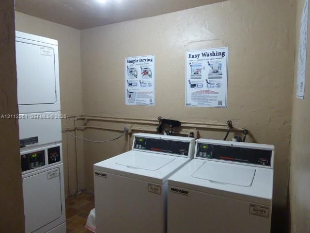 Laundry room in building equipped with a stackable washer and dryer unit, two side-by-side top-load washing machines, and tiled flooring