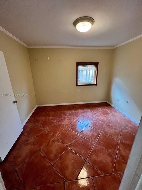 Room featuring diagonal-set tile flooring, neutral wall tones, a single-pane window with wood-finish trim, and a flush-mount ceiling light fixture