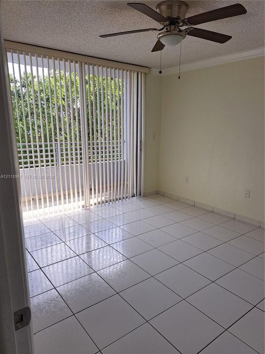 Tiled flooring, ceiling fan with integrated lighting, and full-height sliding glass doors opening to a balcony