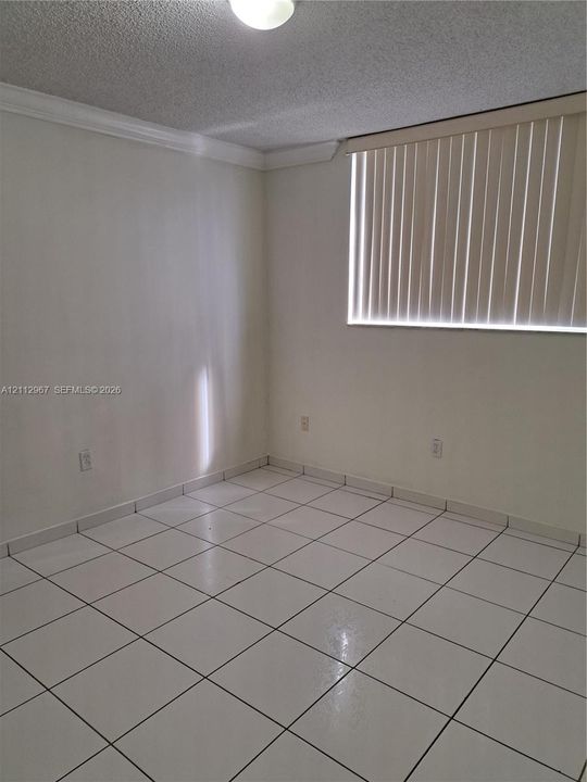 Ceramic tile flooring, neutral wall finishes, crown molding, and vertical window blinds