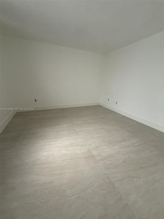Neutral interior space featuring large-format stone-style tile flooring and crisp white wall finishes