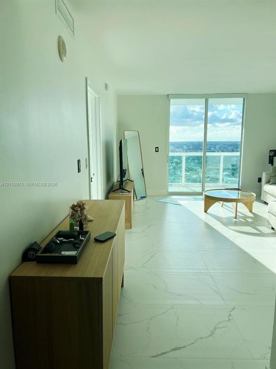 Large-format tile flooring, sliding glass door, and balcony with exterior railing
