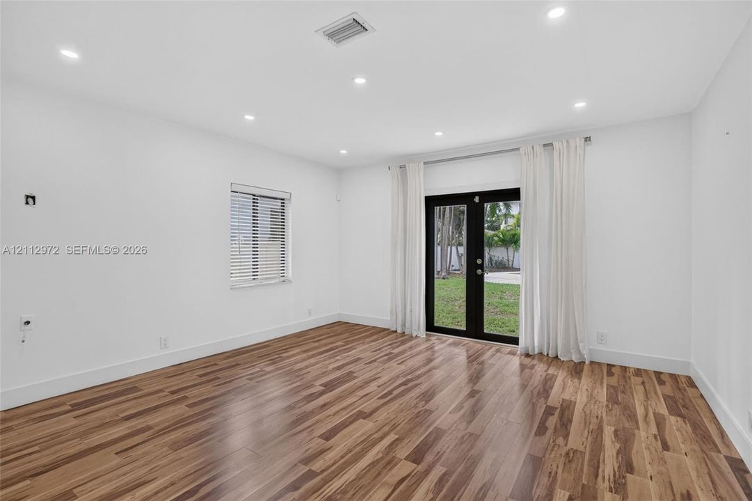 Interior space featuring wood-finish flooring, recessed lighting, and black-framed double glass doors providing an exterior perspective
