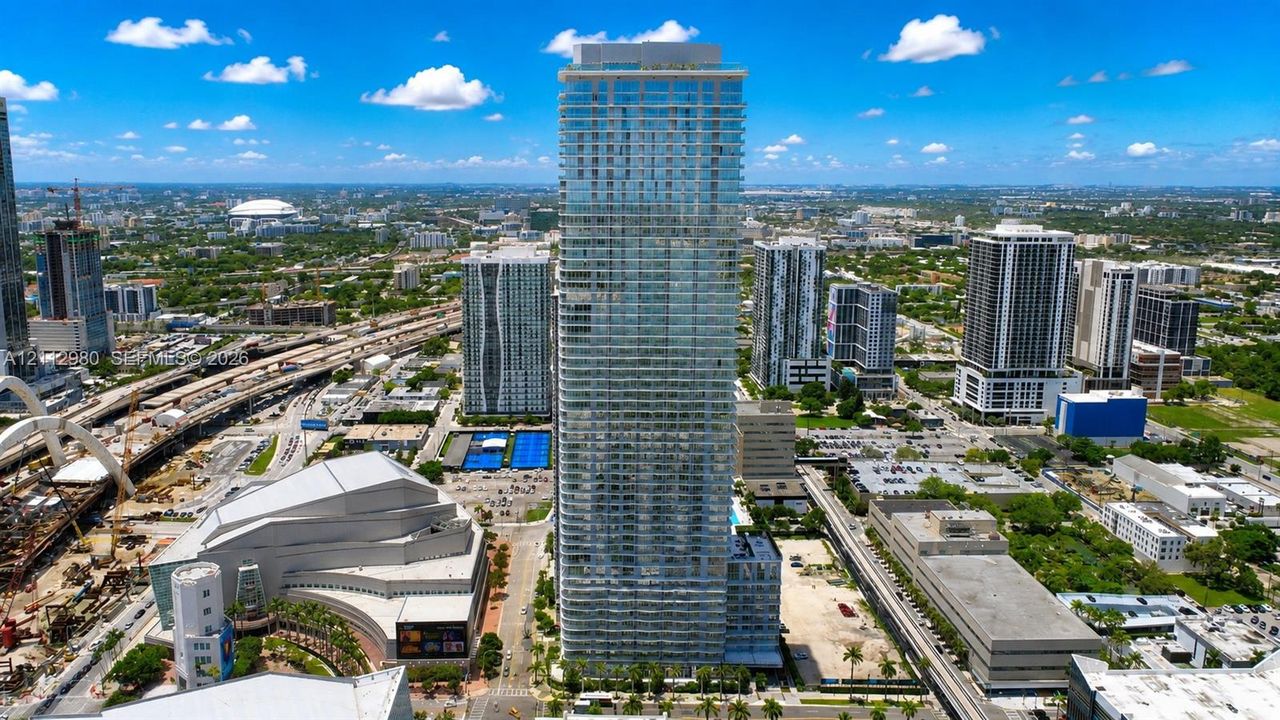 High-rise glass facade residential tower featuring wrap-around balconies and a multi-level concrete structural design