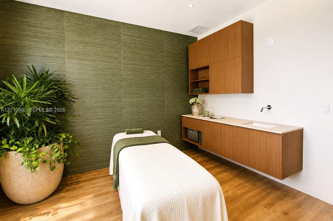 Room featuring green textured wall surfacing, wood-finish flooring, custom floating cabinetry, stone-surface countertop, and wall-mounted sink faucet