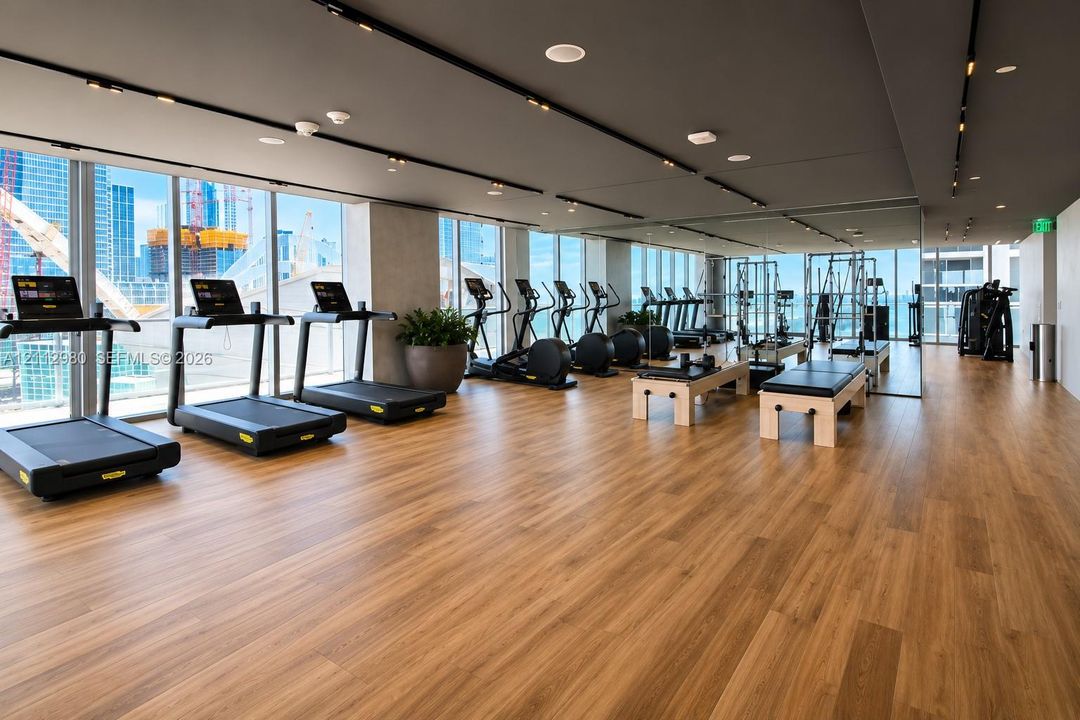 Fitness center featuring wood-finish flooring, floor-to-ceiling windows, mirrored walls, recessed lighting, and track lighting