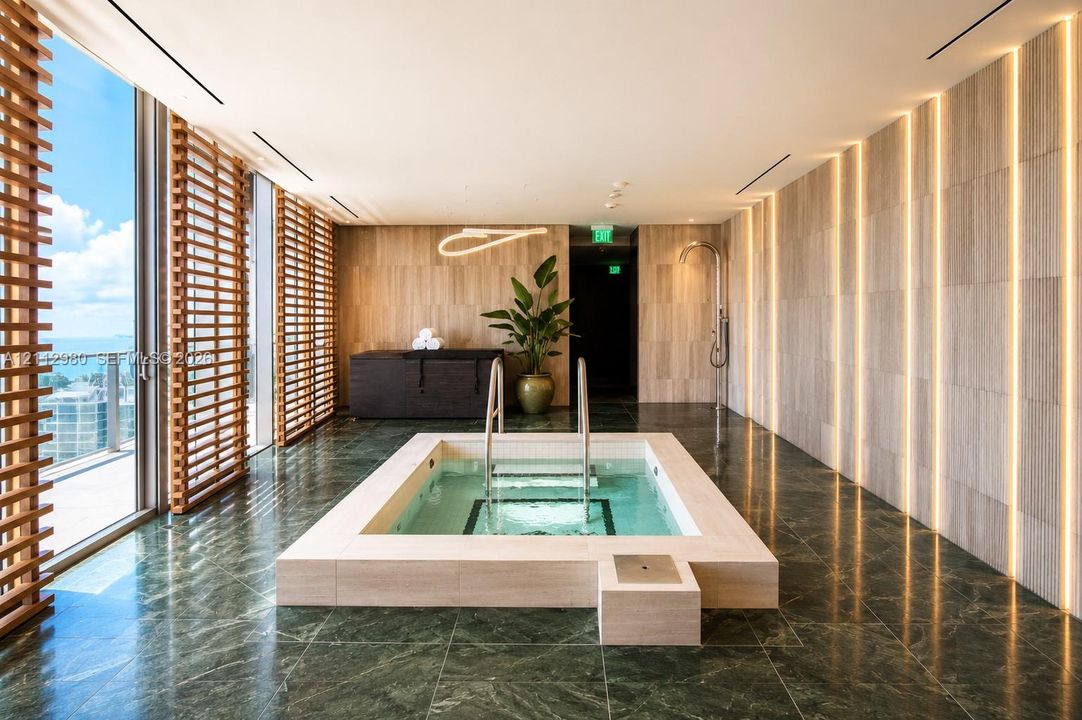 Sunken plunge pool featuring a stone surround, floor-to-ceiling wall paneling with integrated recessed lighting, green tile flooring, and floor-to-ceiling wooden privacy slats