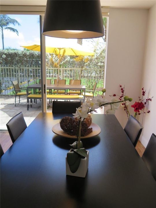 Dining area featuring a large, matte-finish pendant light fixture and a sliding glass door opening to a paved patio