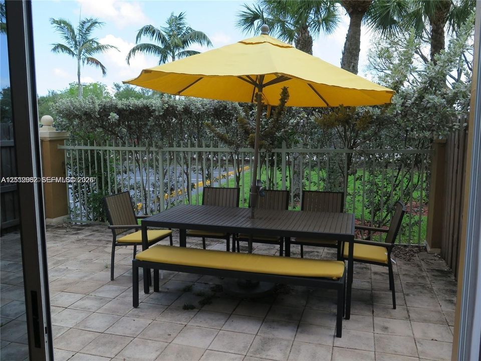 Private patio featuring concrete tile flooring, a metal picket perimeter fence, and integrated pillar columns