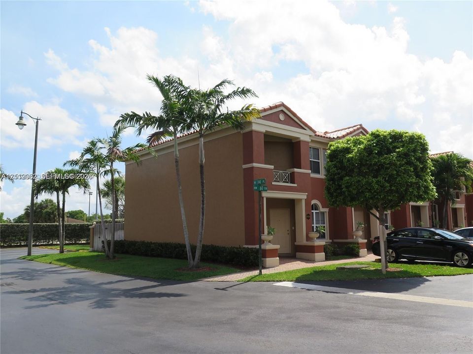 Two-story exterior featuring a terra cotta roof, stucco facade, decorative second-story balcony with metal railing, and paver entryway