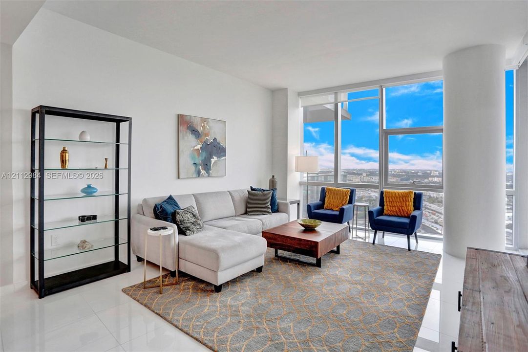 Living area featuring floor-to-ceiling windows, polished tile flooring, and a prominent structural column