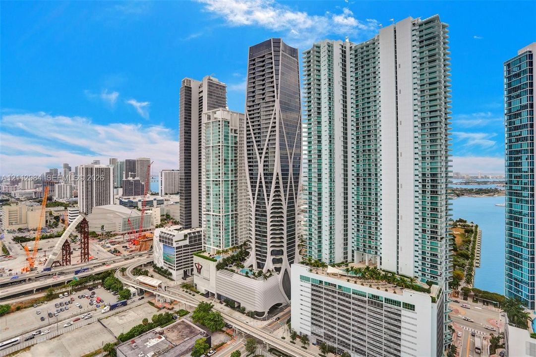 High-rise residential tower featuring a distinct exoskeleton facade, floor-to-ceiling glass paneling, and elevated outdoor terrace levels