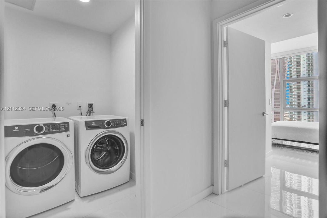 Laundry area featuring side-by-side front-load washer and dryer, recessed ceiling lighting, and polished tile flooring