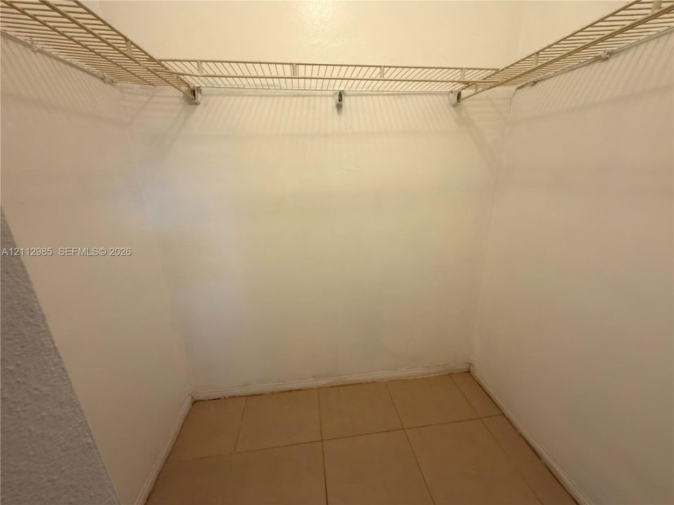 Walk-in closet featuring floor-to-ceiling tile flooring and dual-level wire shelving
