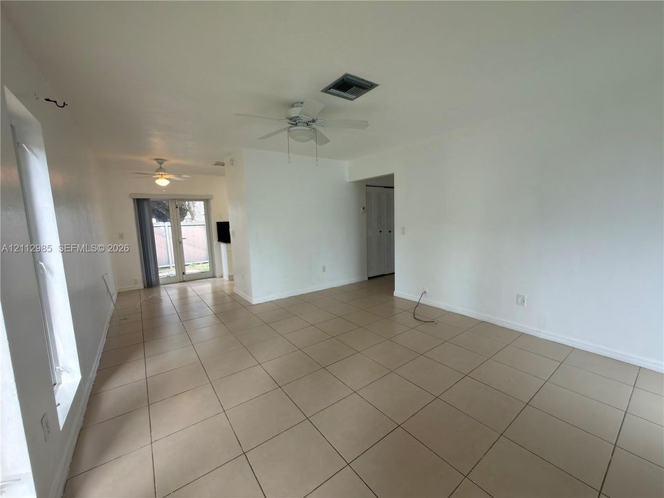 Large-format tile flooring, dual ceiling fans, and sliding glass exterior doors