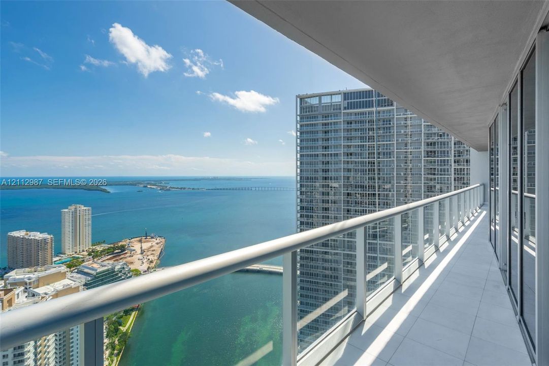 Covered balcony featuring tile flooring and a glass-paneled railing