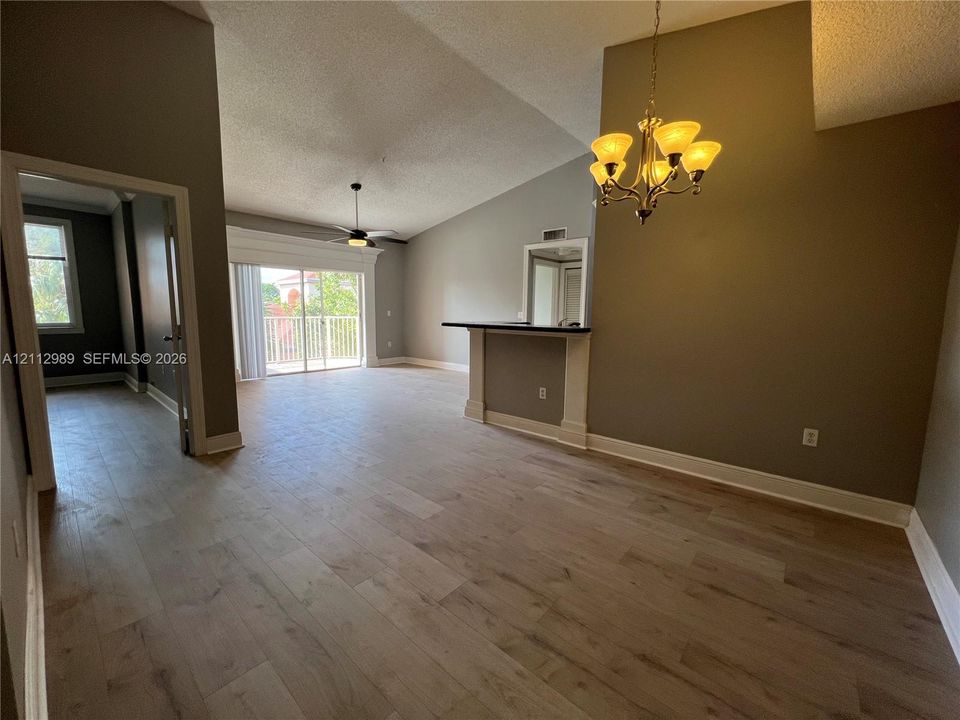 Vaulted ceilings, wood-finish flooring, built-in bar, and multi-light chandelier