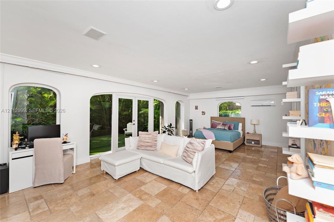 Spacious interior featuring stone tile flooring, recessed lighting, arched windows, dual-pane glass French doors, and white built-in wall shelving