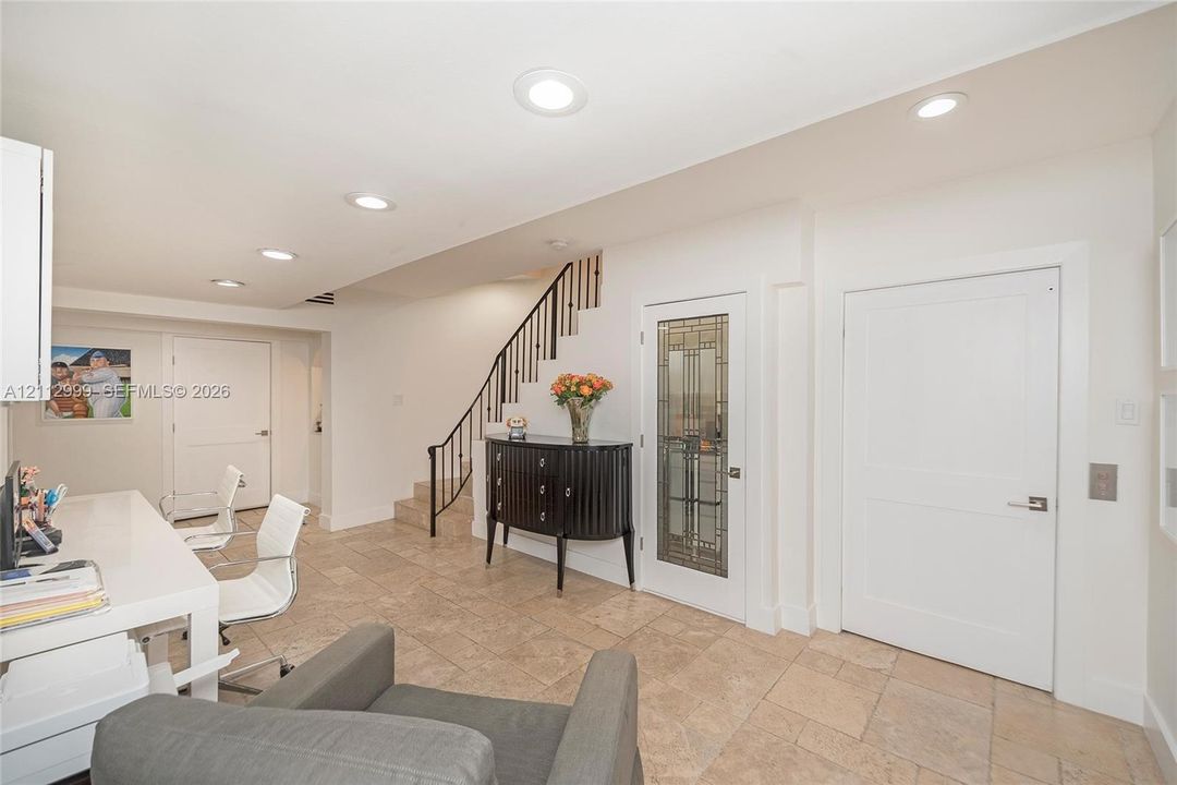 Tiled flooring, recessed lighting, staircase with metal railing, and glass-paneled interior door