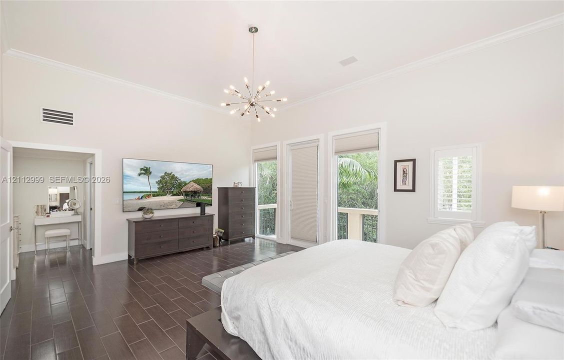 High ceilings, dark tile flooring, multi-arm sputnik chandelier, and expansive windows with custom roller shades