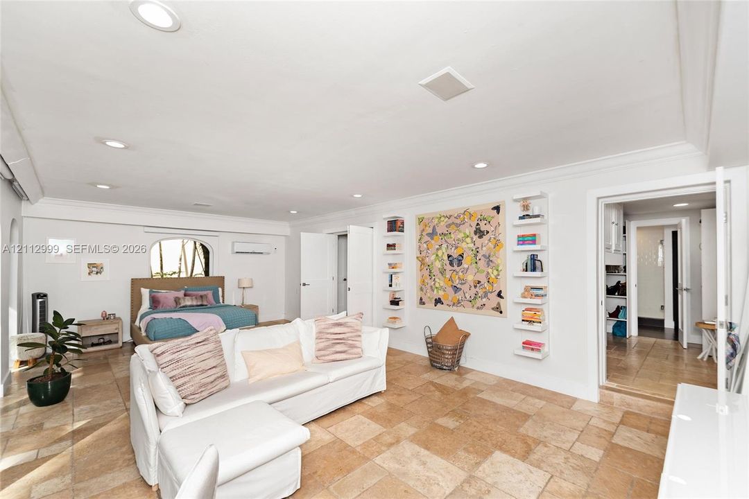 Large-format stone flooring, recessed ceiling lighting, wall-mounted floating shelves, and crown molding