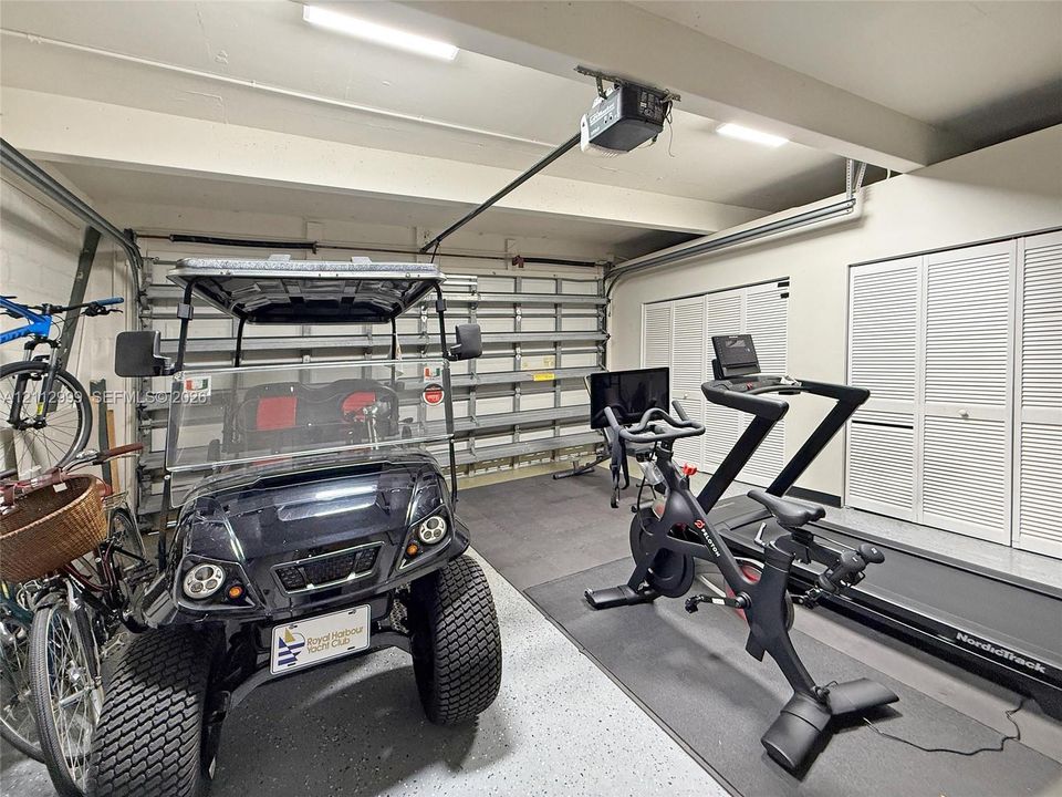 Multi-car garage featuring epoxy-coated flooring, built-in wall shelving, and dual sets of louvered-door closets