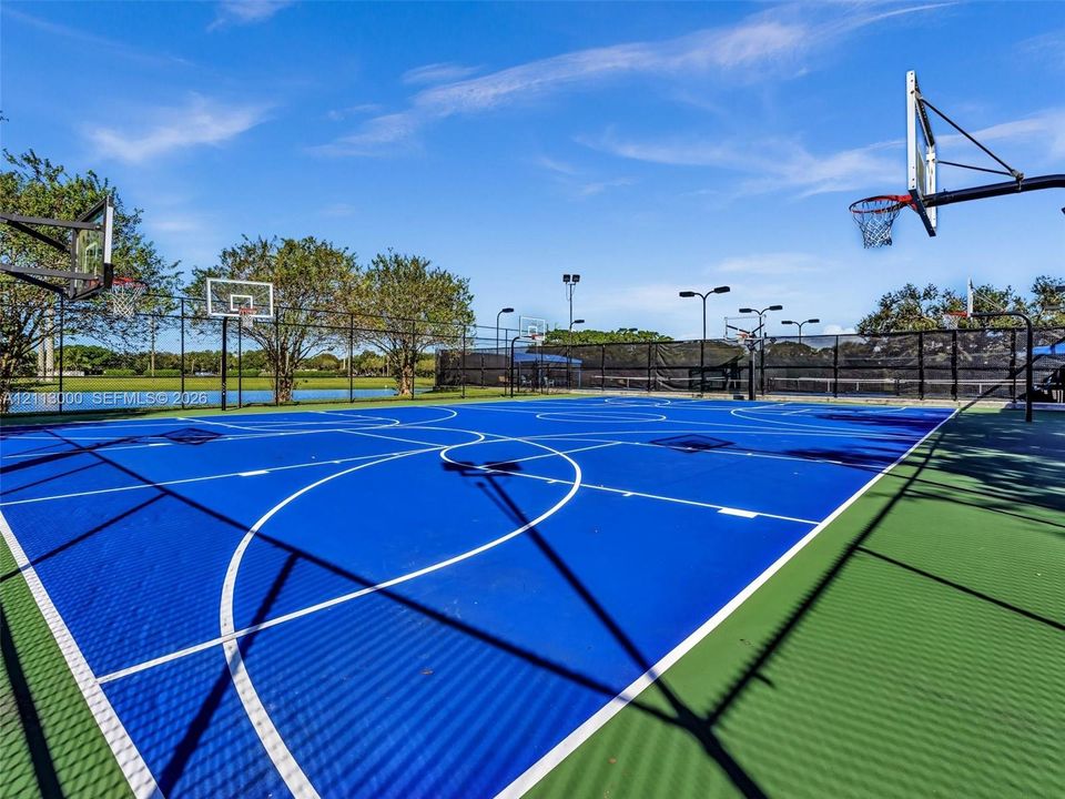 Multi-purpose sports court featuring a high-performance surface, multiple basketball hoops, stadium-style lighting, and perimeter fencing