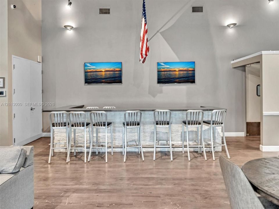 Built-in bar featuring a stacked-stone facade, flat-surface countertop, and high-reaching ceilings with wall-mounted lighting