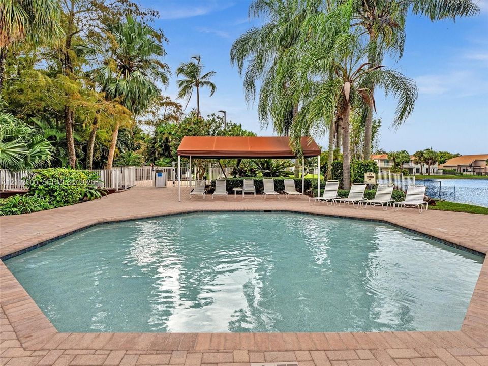 Swimming pool featuring a paver deck, permanent poolside canopy, and water backdrop