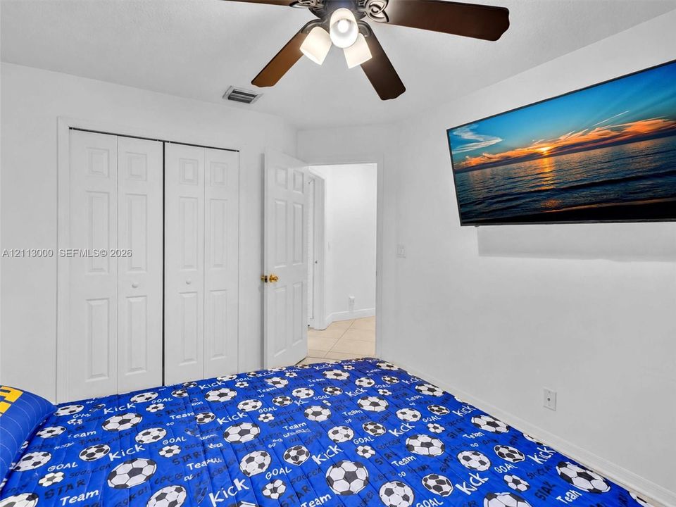 Interior room featuring white walls, a multi-blade ceiling fan with integrated lighting, and a double-door closet