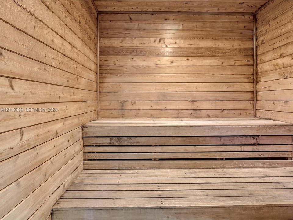 Sauna room with tongue-and-groove wood wall paneling and tiered wood-finish benches
