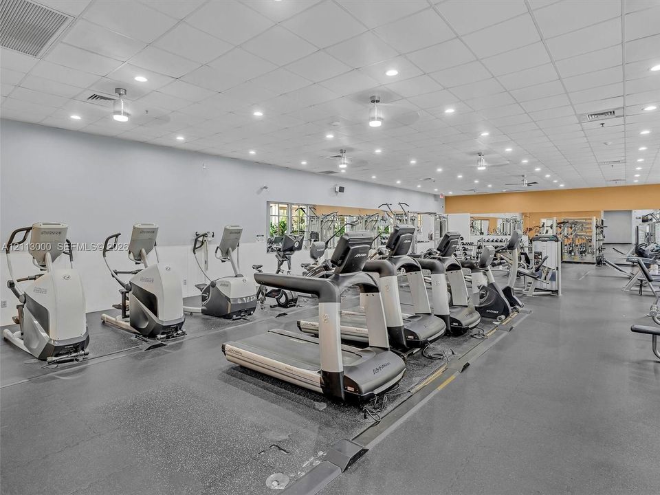 Fitness center featuring high-contrast rubber flooring, recessed ceiling lighting, and wall-to-wall mirrors