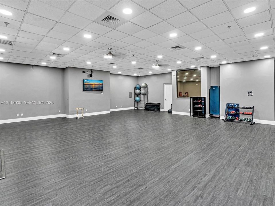 Expansive multipurpose space featuring wood-finish flooring, recessed lighting, drop ceiling, and integrated ceiling fans