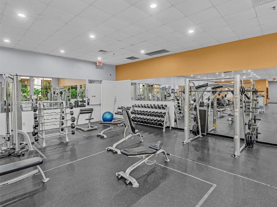 Fitness center featuring wall-to-wall mirrors, durable rubberized flooring, and recessed ceiling lighting