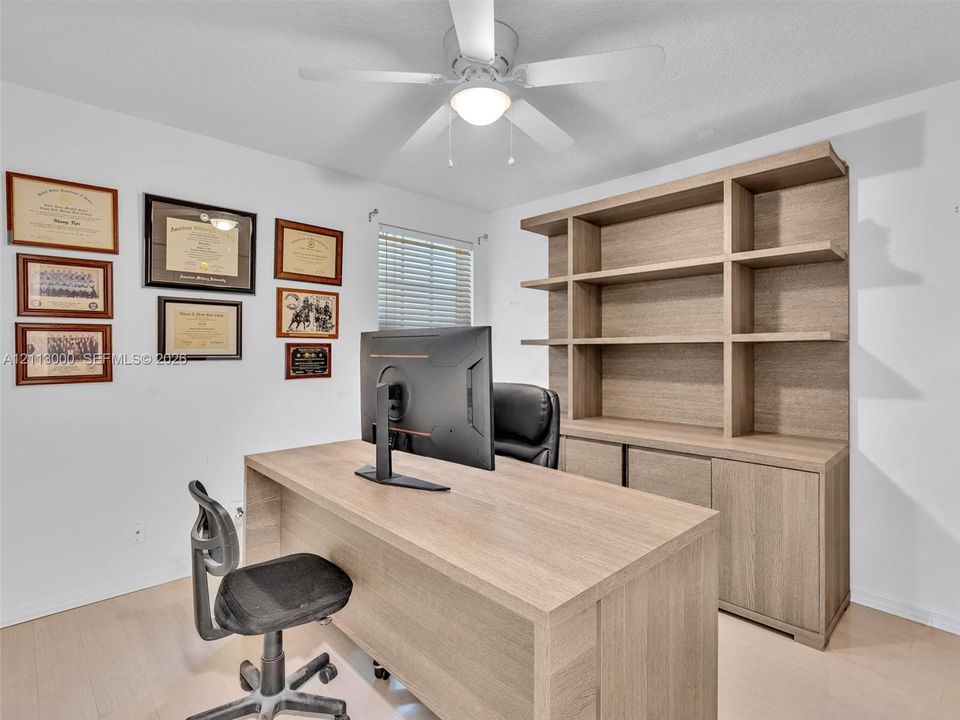 Built-in floor-to-ceiling wood-finish cabinetry, wood-finish flooring, and overhead ceiling fan with integrated light fixture