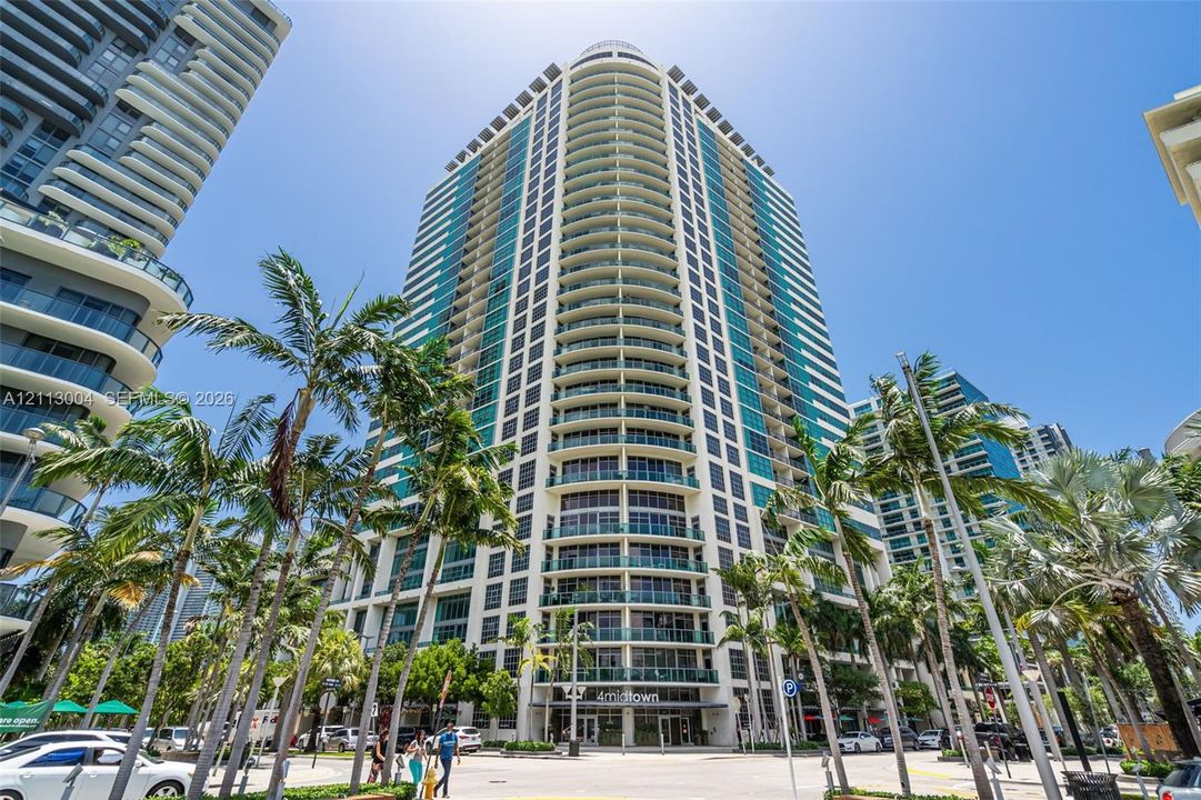 High-rise residential tower featuring a glass facade, expansive floor-to-ceiling windows, private balconies, and concrete structural elements