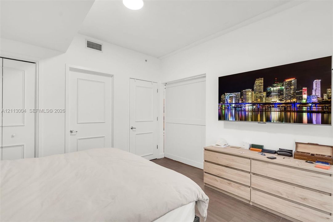 Interior space featuring wood-finish flooring, two-panel interior doors, and a wall-mounted flat-panel television