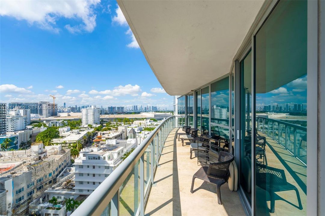Curved balcony featuring stone tile flooring and a glass railing