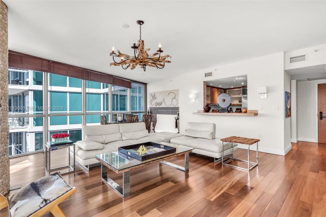 Living area featuring floor-to-ceiling windows, wood-finish flooring, a rustic chandelier, and a built-in pass-through window with a ledge