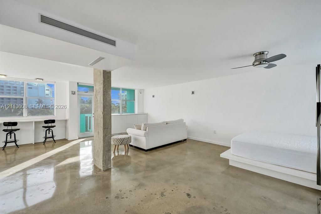 Polished concrete flooring, exposed concrete structural column, built-in desk counter, recessed lighting, and ceiling-mounted fan