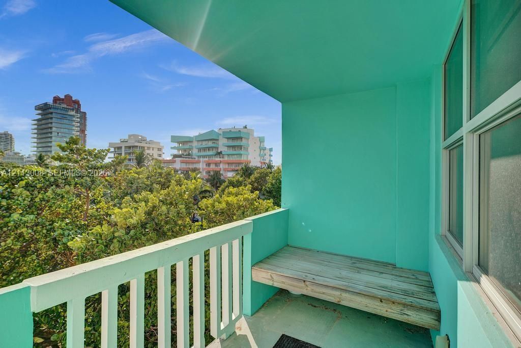 Private balcony featuring a built-in wooden bench, painted concrete surfaces, and metal railings