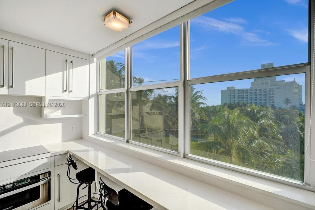 White cabinetry, expansive window wall, integrated stone-surface countertop, and flush-mount ceiling lighting