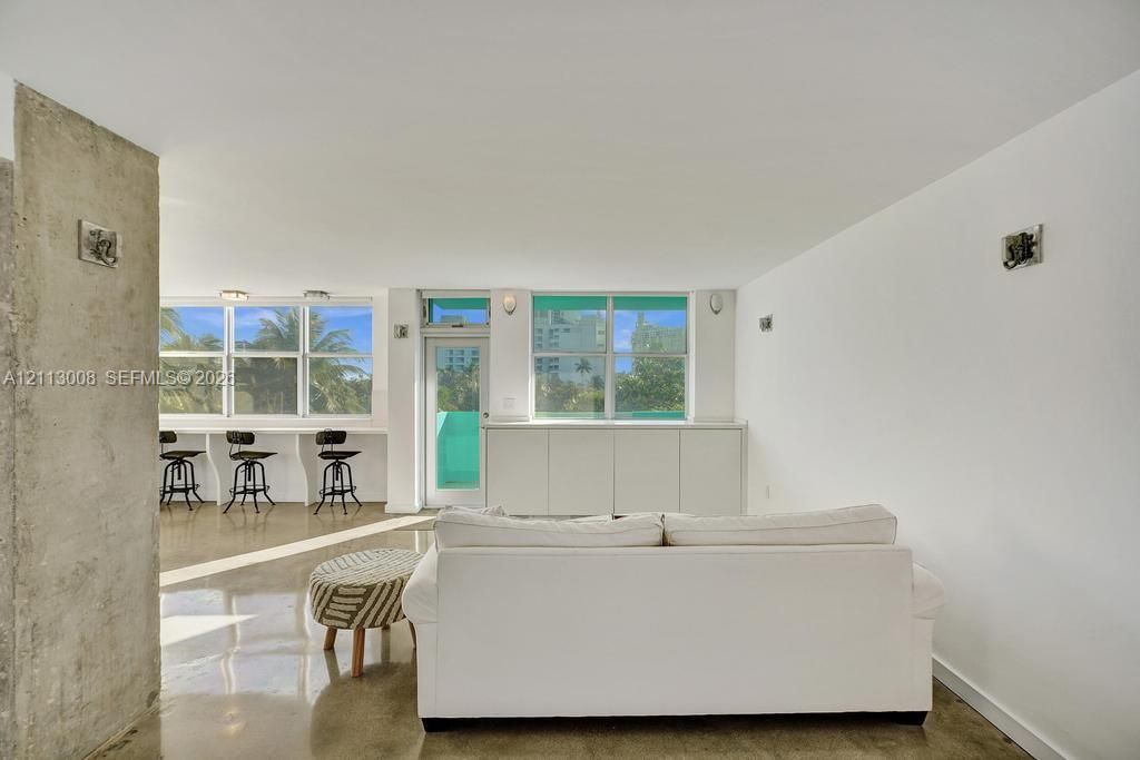 Polished concrete flooring, exposed concrete structural column, built-in lower cabinetry, and expansive windows with glass entry door