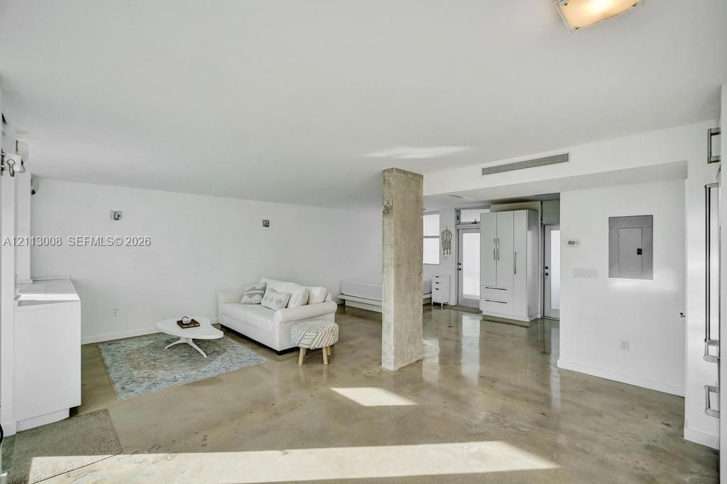 Open-concept interior featuring polished concrete flooring, an exposed structural concrete column, recessed lighting, and built-in white cabinetry
