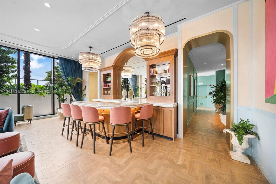 Built-in wet bar featuring custom wood cabinetry, stone countertop, mirrored backsplash, tiered crystal chandeliers, and parquet wood-finish flooring