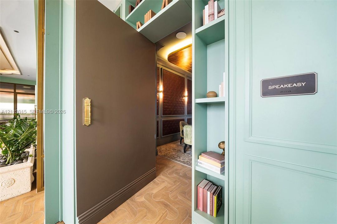 Pivot door with brass hardware, custom built-in cabinetry, herringbone-pattern wood flooring, and recessed ceiling lighting